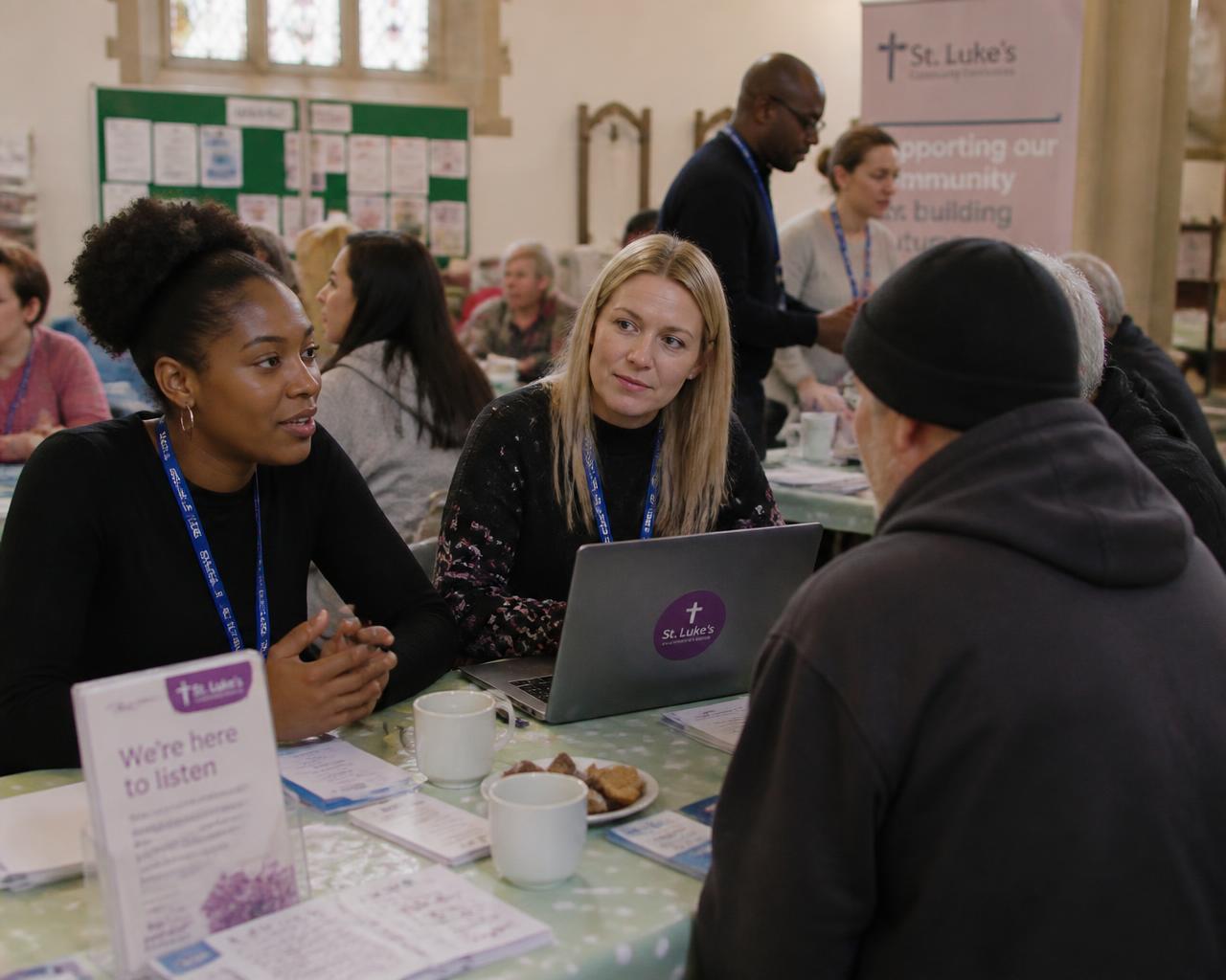 Charity outreach workers speaking with a community member at a church community centre session
